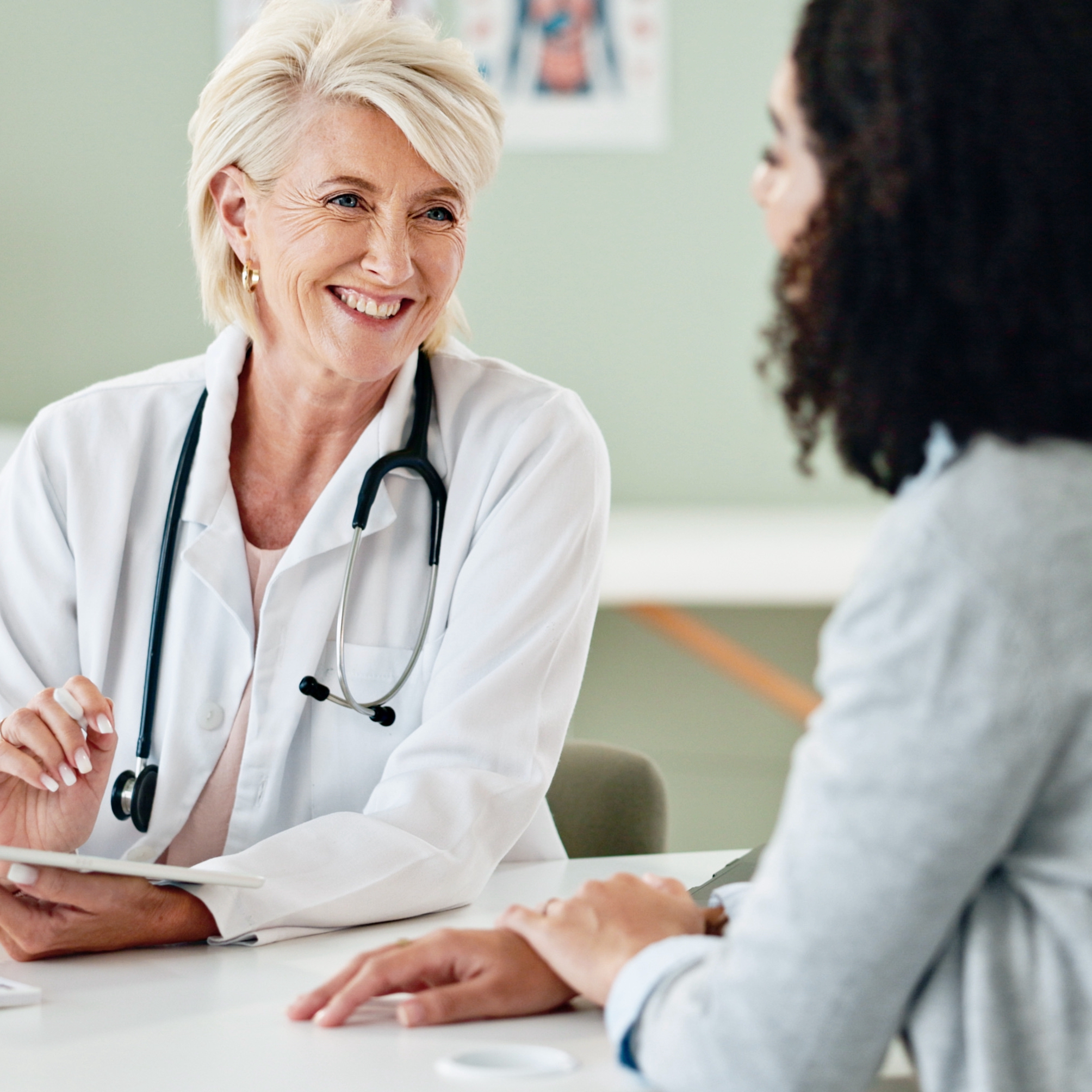 Happy woman, tablet and consulting with patient for medical results, diagnosis or prescription at hospital. Mature person or cardiologist talking to client in consultation with technology at clinic